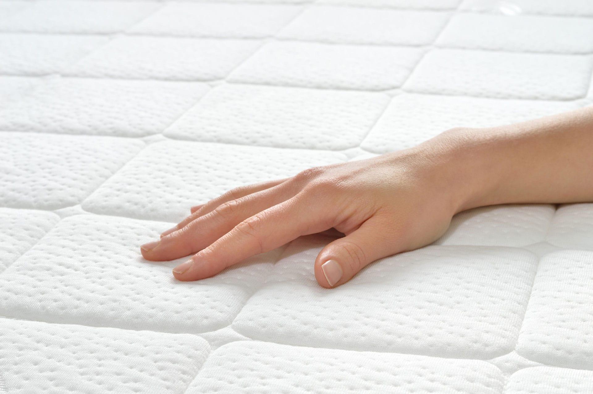 Mattress Zone background image. A hand on a mattress.